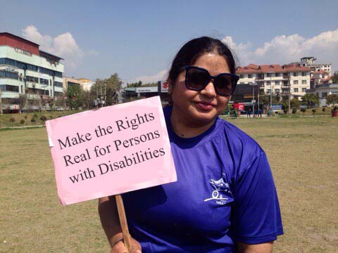 a lady carrying a play card to make the right real for persons with disabilities for Disability Human Rights Promotion Society Kathmandu (DHRPS)