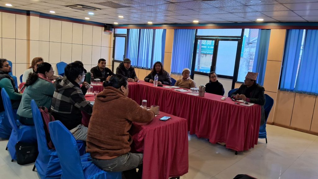 Participants sitting in a U shaped table and discussing.